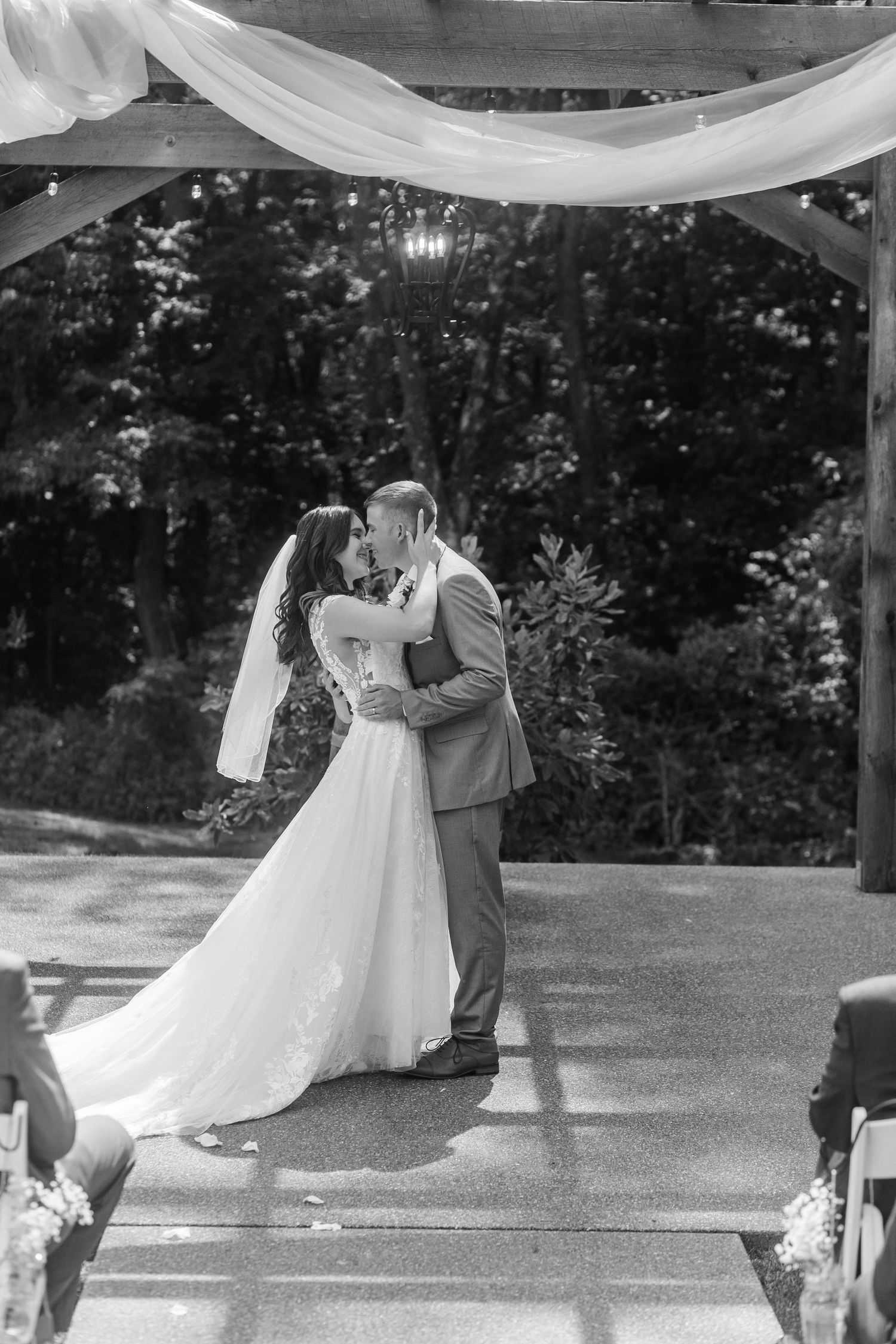 Couple shares intimate first dance moment under draped white fabric at outdoor wedding venue.