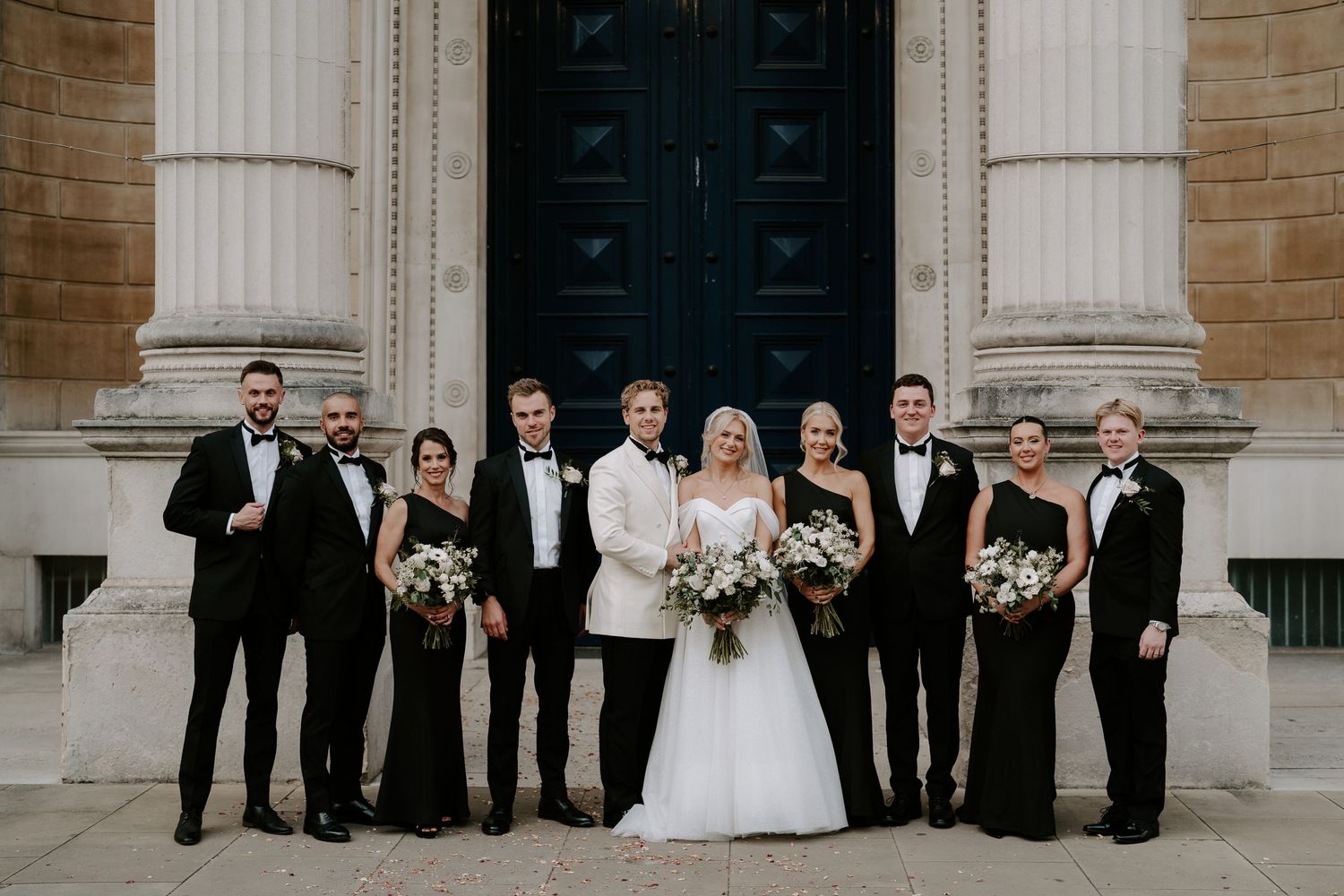 bride and groom and wedding party smiling for a portrait outside the Ashmolean Museum in oxford