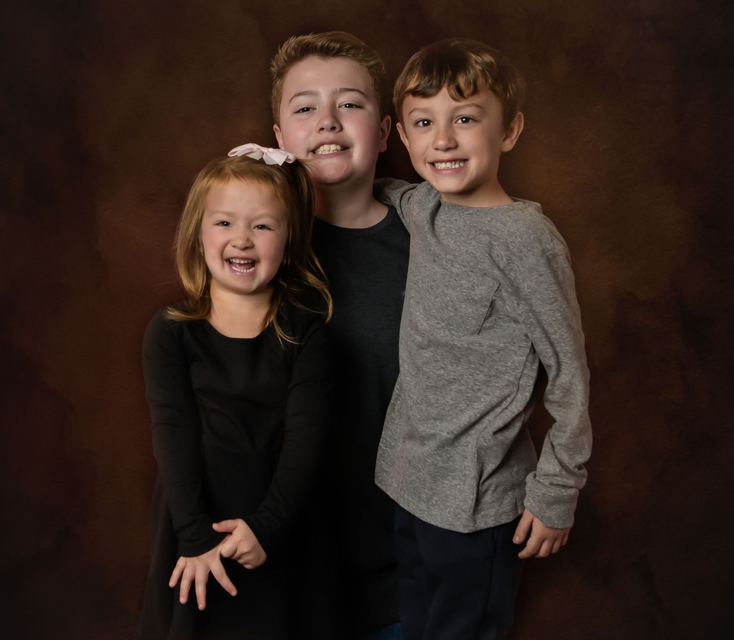 A playful studio portrait session with children against a dark background.