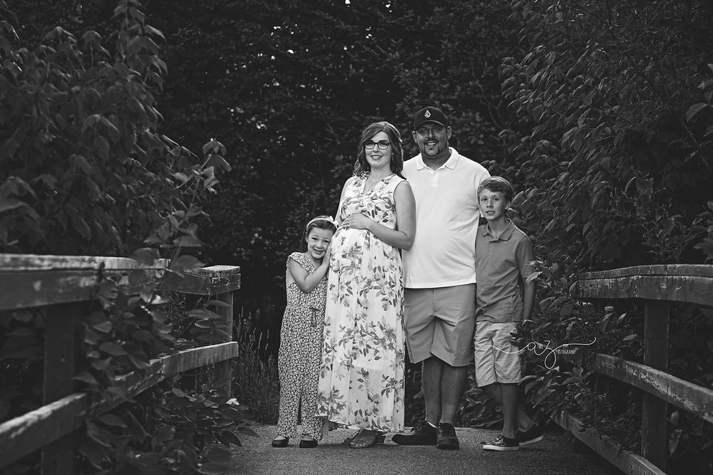 A family stands together on a wooden bridge in black and white.