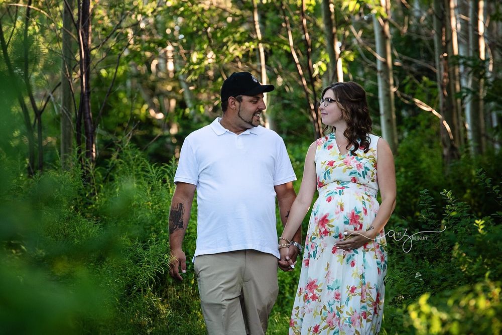 A couple walks hand in hand through a sunlit forest path.