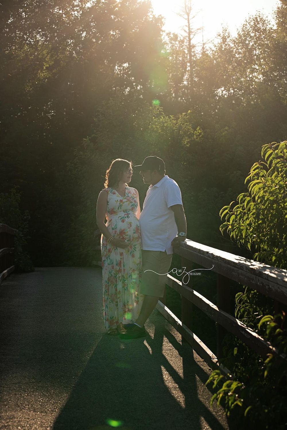 A couple shares an intimate moment on a wooden bridge at sunset.