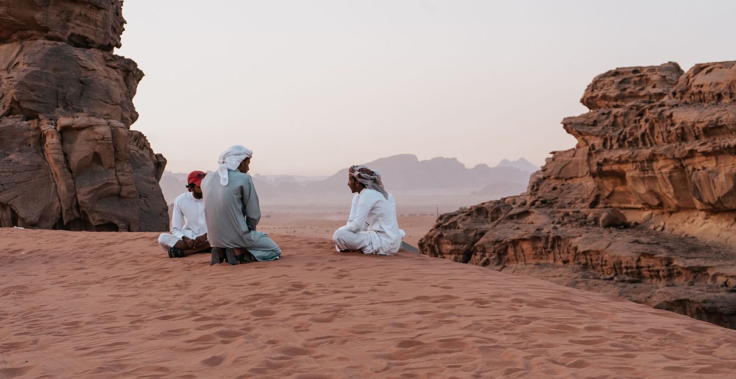 Drie locals zittend in de Wadi Rum woestijn in Jordanië