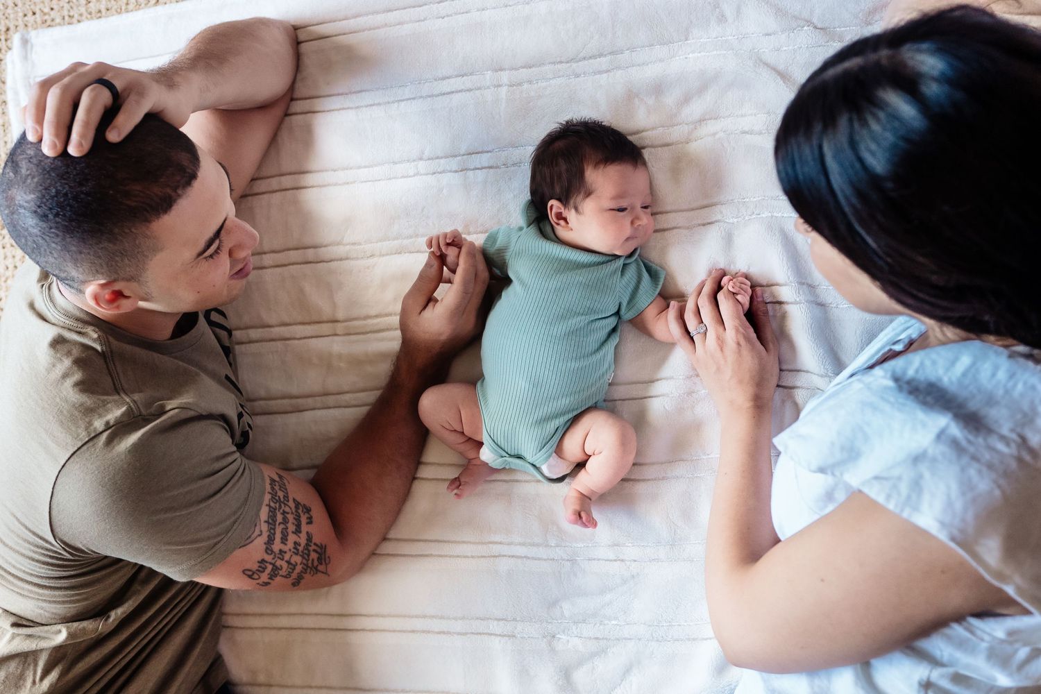 mom and dad with newborn baby on blanket