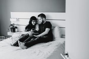 Intimate black and white maternity photos of couple relaxing on bed.