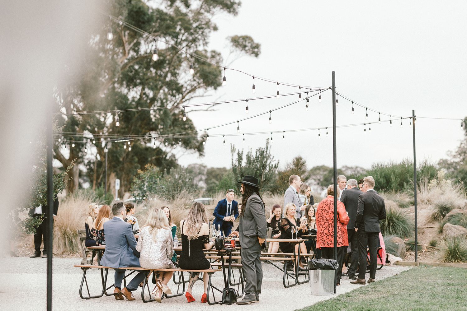 Outdoor wedding reception setup with string lights and rustic decor.