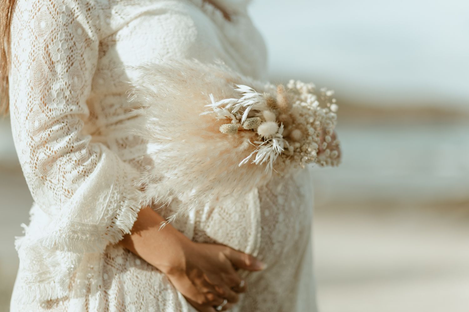 Delicate white dried flowers held against a lace maternity dress.