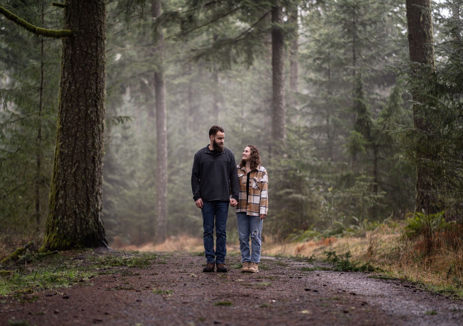 A couple walking together on a misty forest trail.