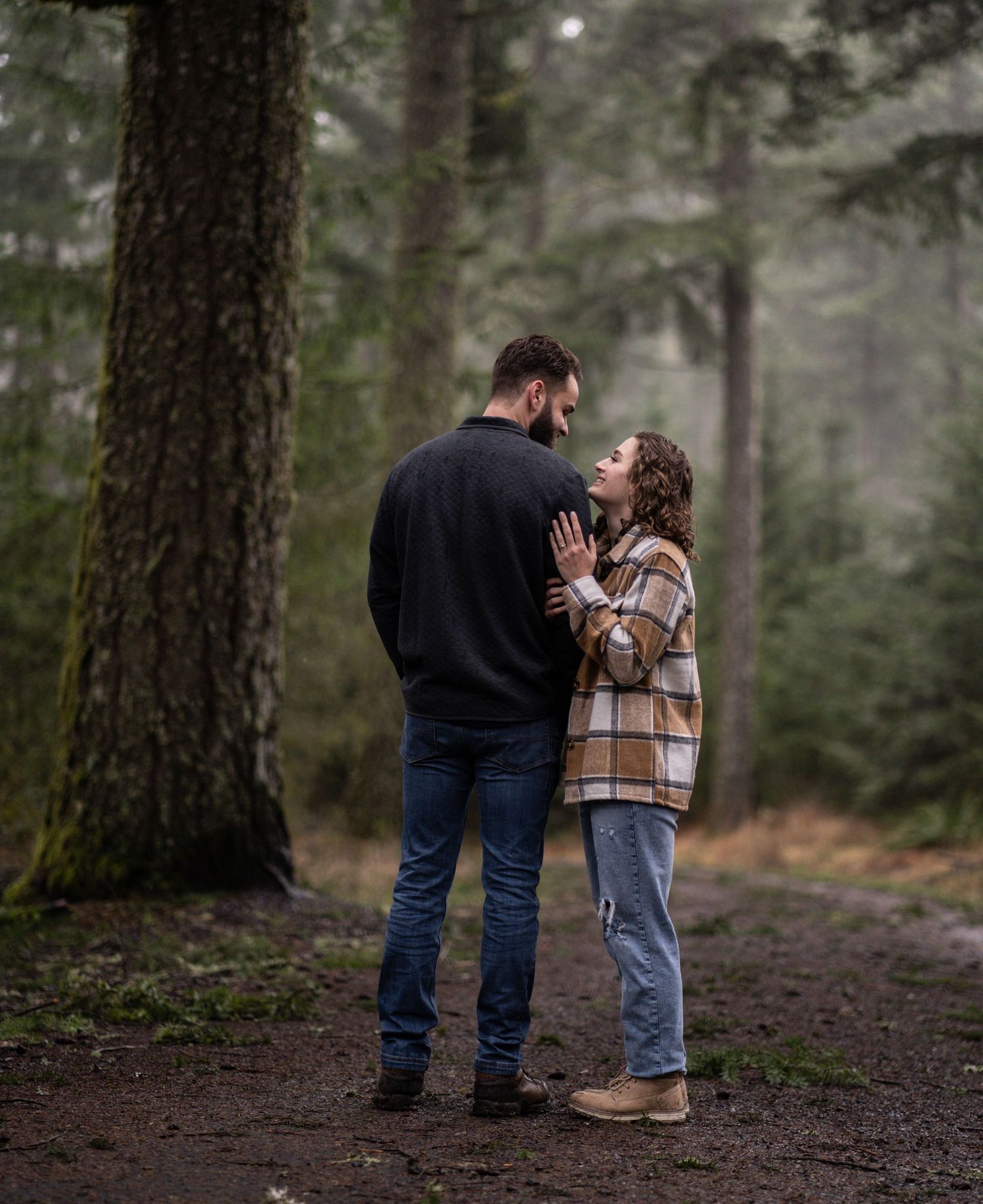 A romantic moment between a couple on a wooded trail.