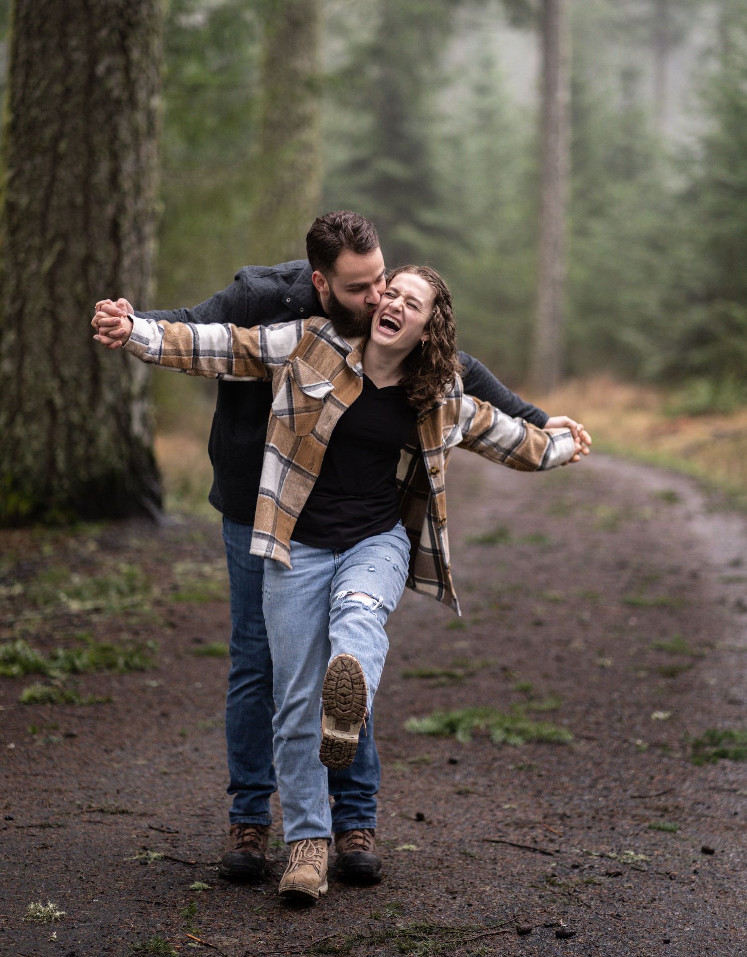 A playful couple enjoying a moment together on a forest path.