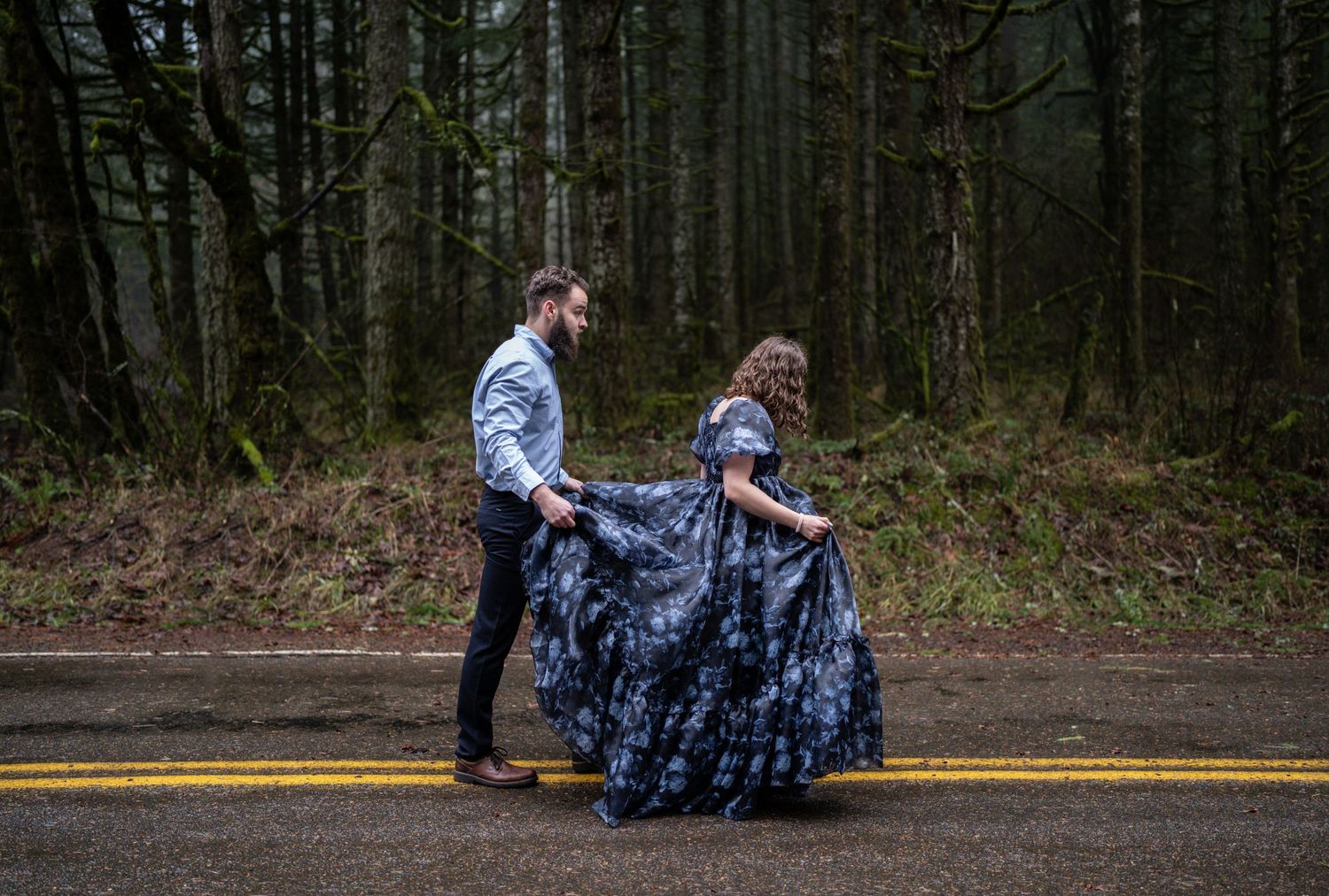 A couple dancing on a forest road with a flowing blue dress.