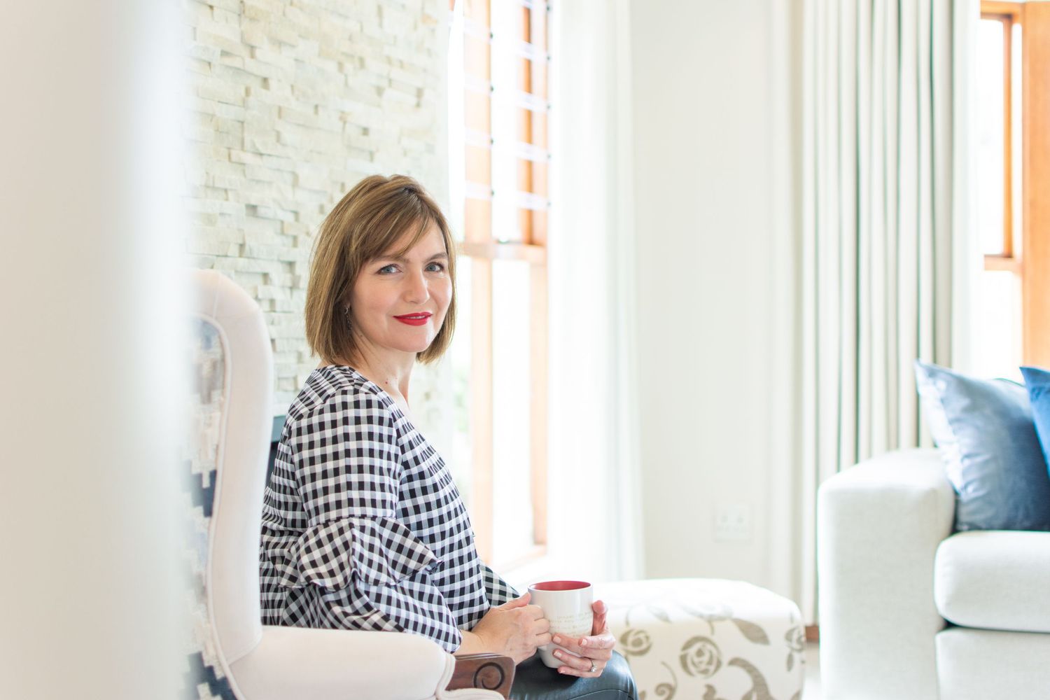 Relaxed moment in a bright living room with houndstooth pattern chair and white decor.