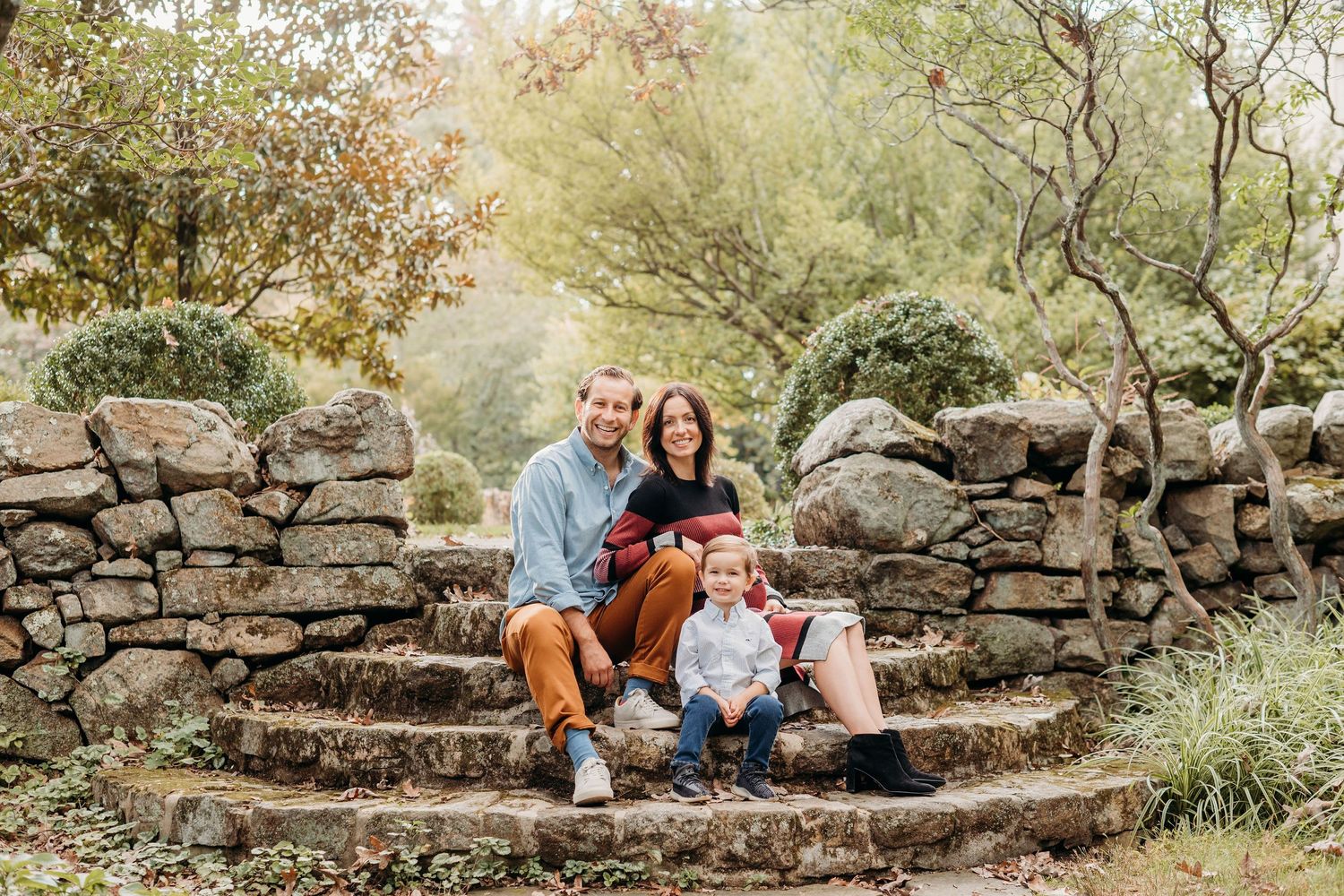 Group enjoying autumn day while seated on rustic stone steps surrounded by fall foliage in outdoor garden setting at Cross Estate Gardens.
