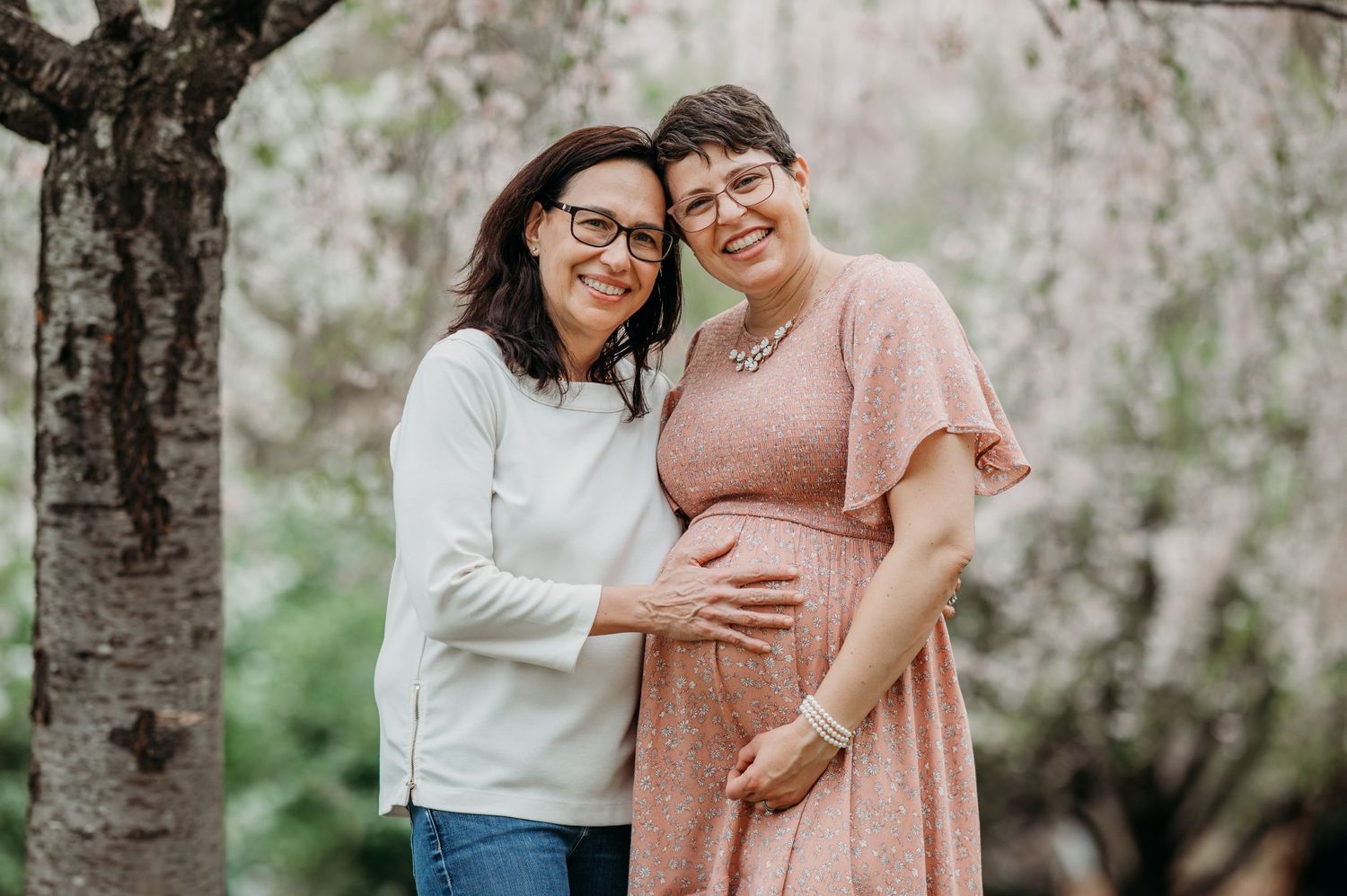 An LGBTQ+ couple shares a tender moment under blooming cherry blossoms in Branch Brook Park.
