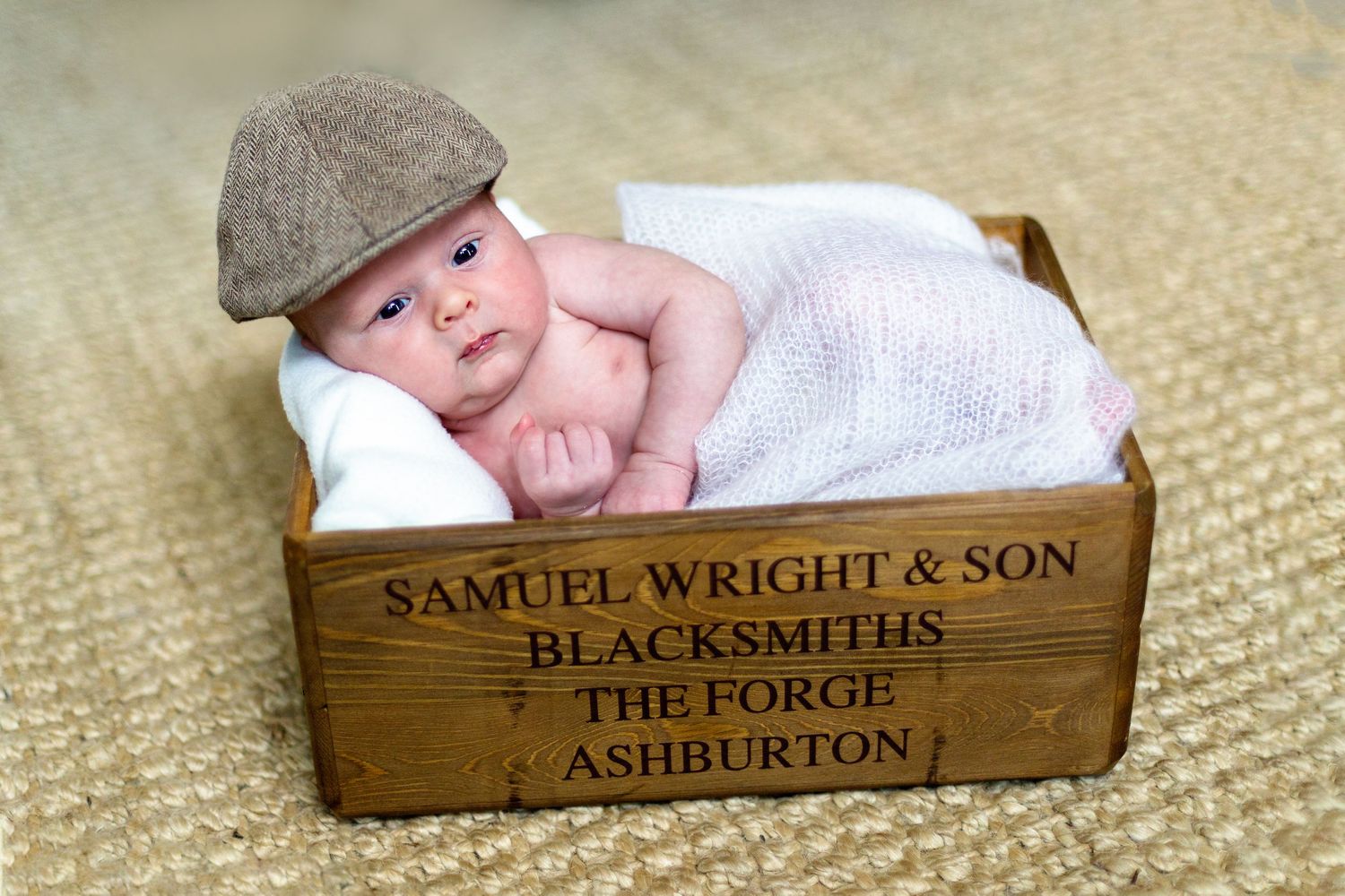 newborn baby boy with cap on lying in a brown box