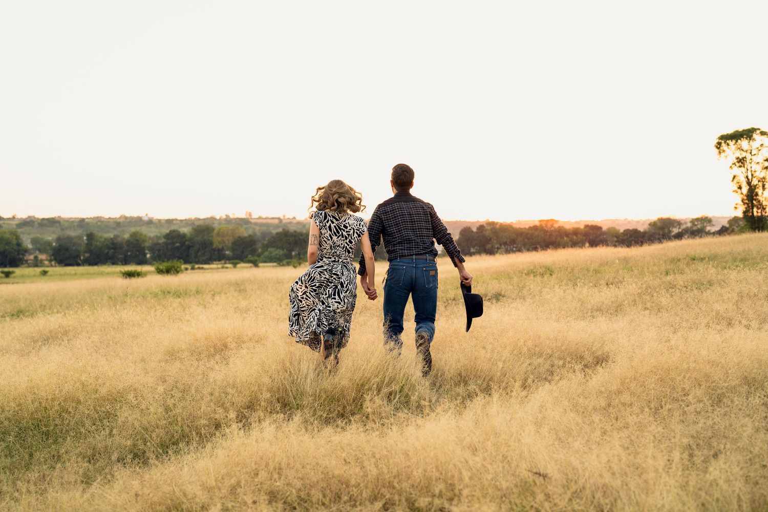Family walking through golden wheat field during sunset photography session.