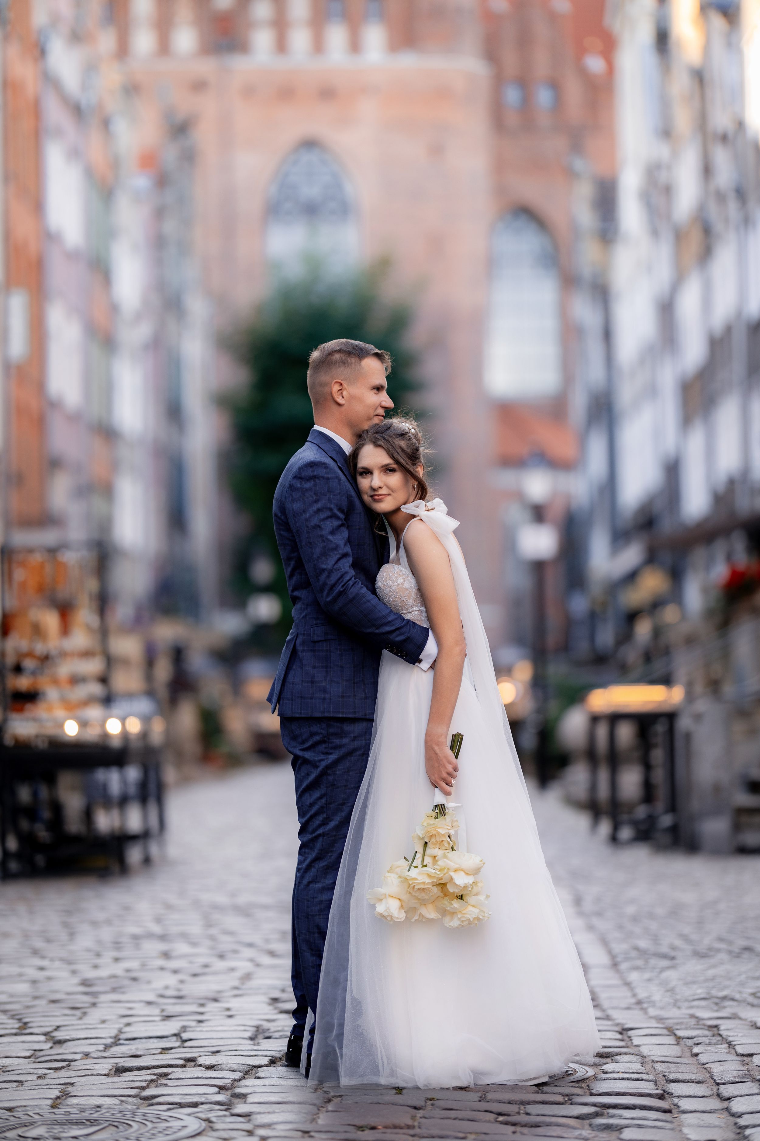 An intimate wedding portrait on cobblestone streets with warm evening light.