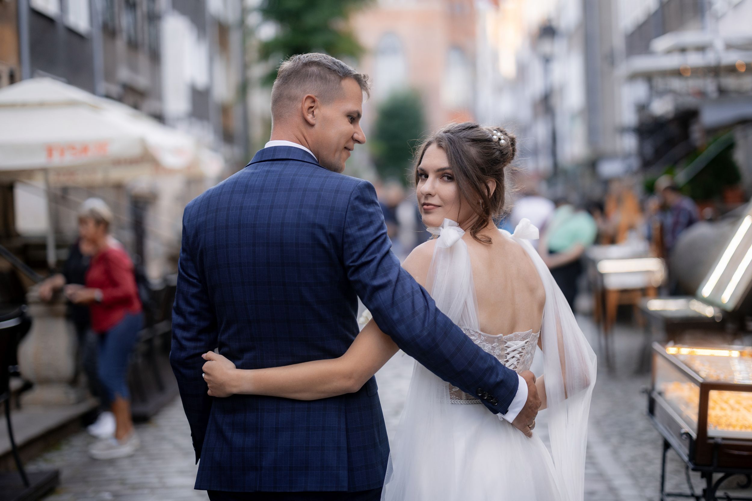 A tender embrace between newlyweds on a charming European cobblestone street.