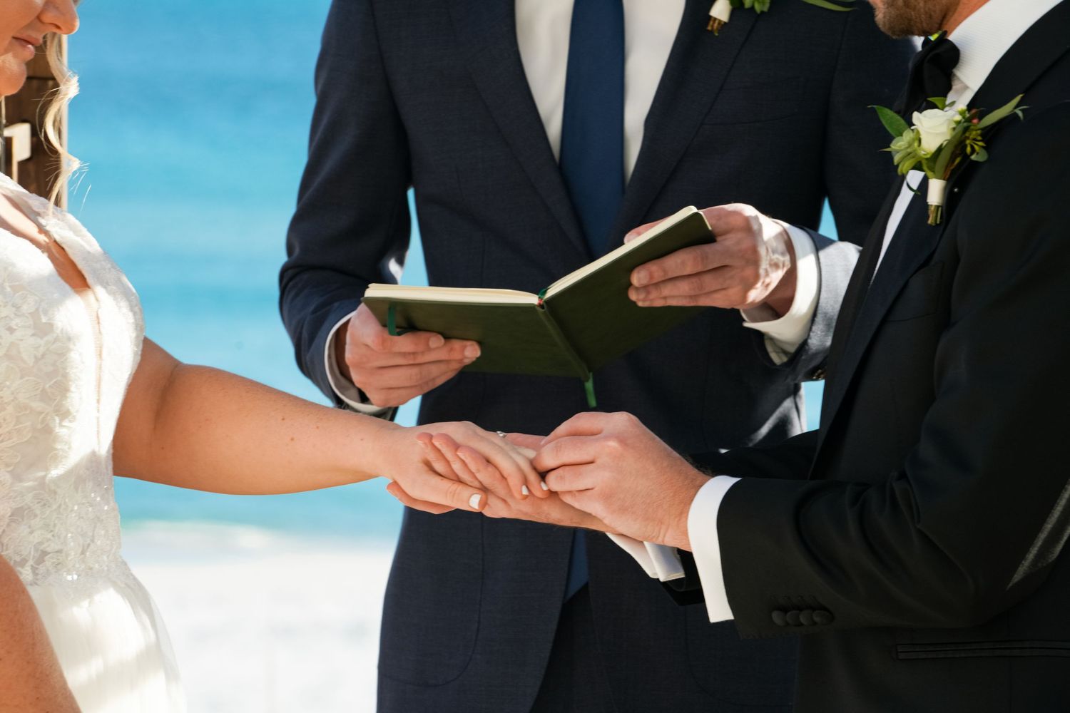 Close-up of wedding ceremony ring exchange on beach.