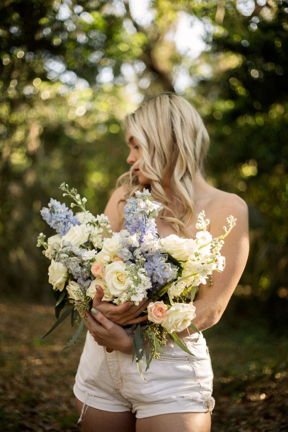 A dreamy summer portrait with a lush bouquet of blue and white flowers.