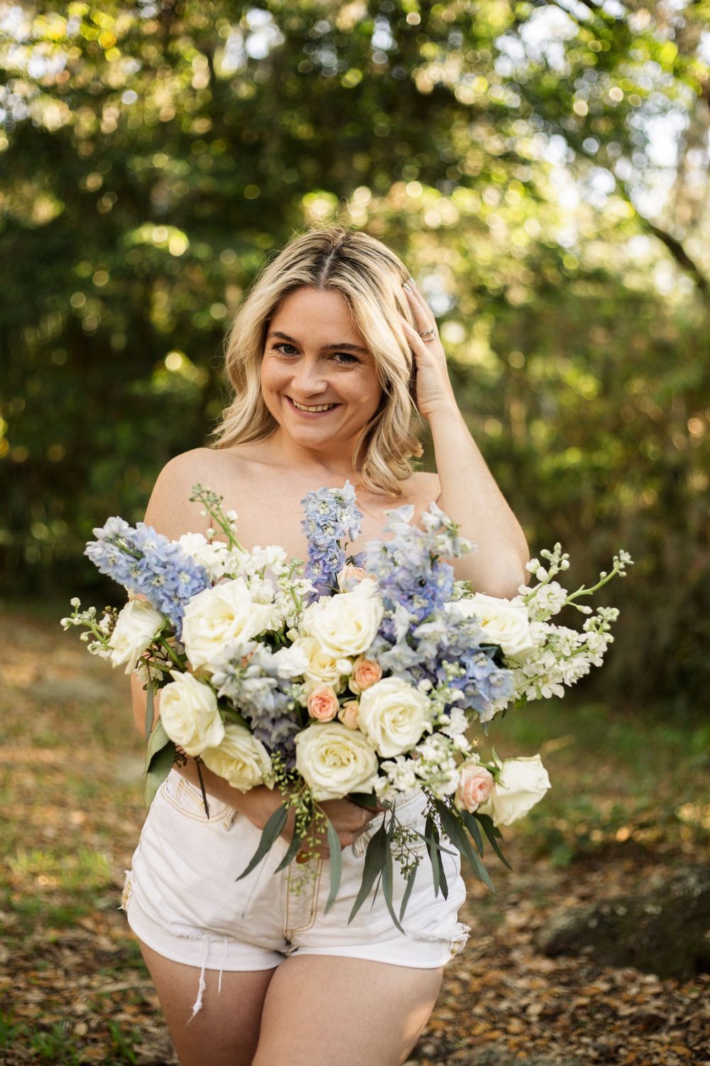Natural light portrait with a stunning arrangement of white roses and blue flowers.