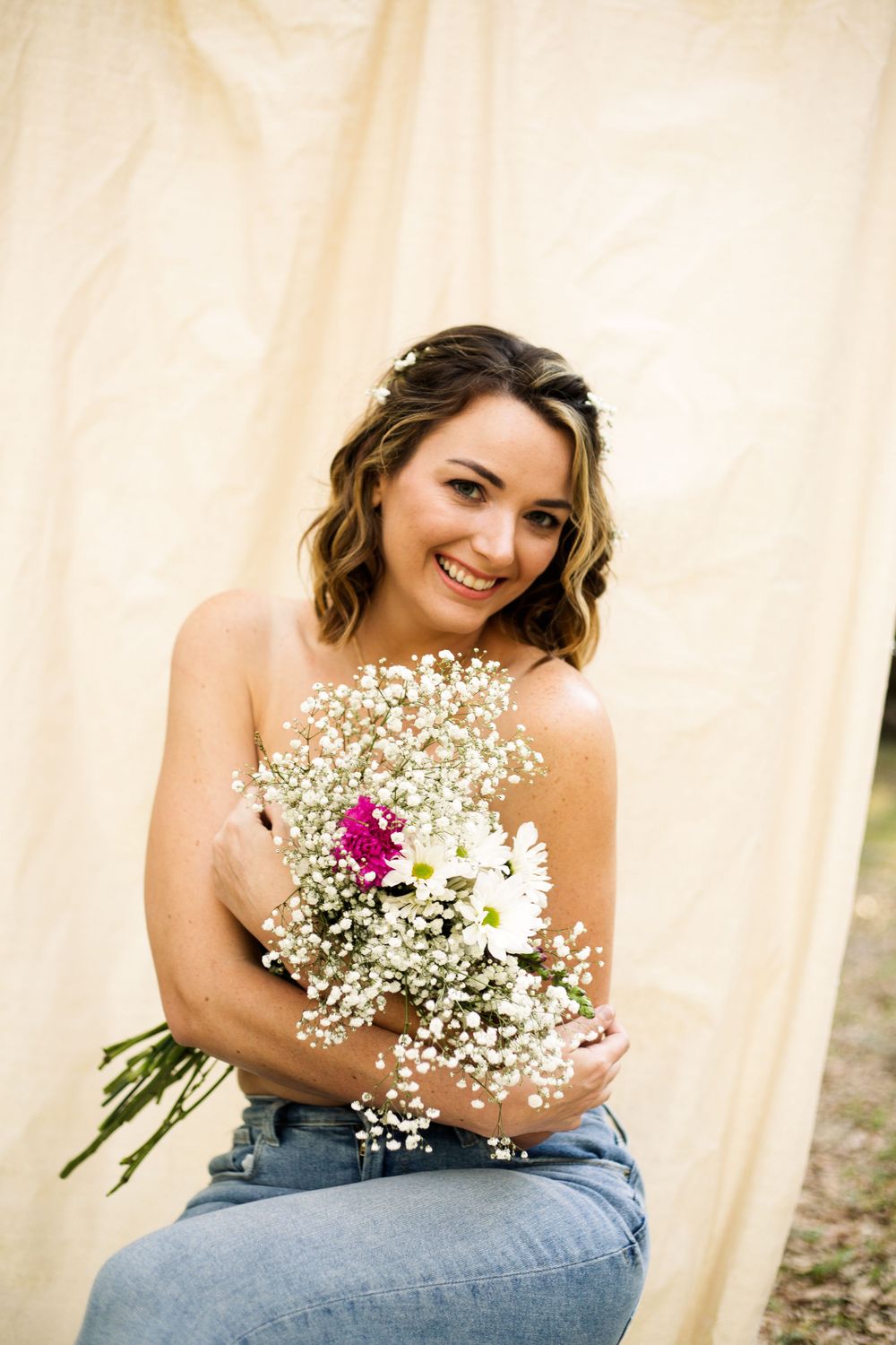 Boudoir style portrait with baby's breath bouquet against cream backdrop.