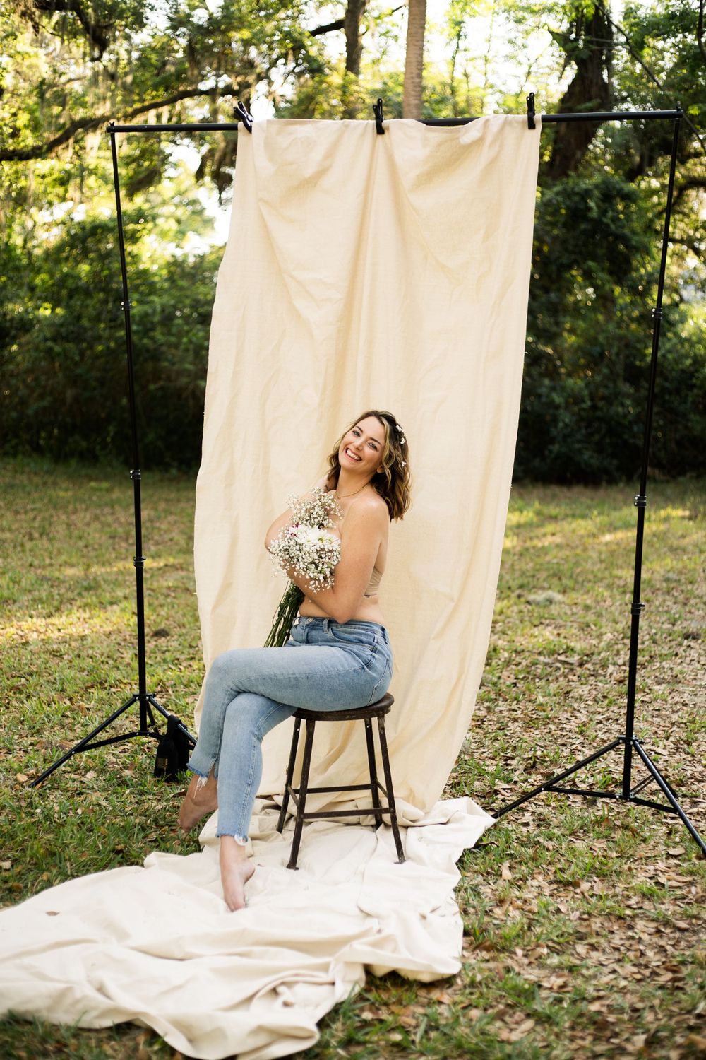 Joyful portrait against draped fabric backdrop in sunlit outdoor setting.