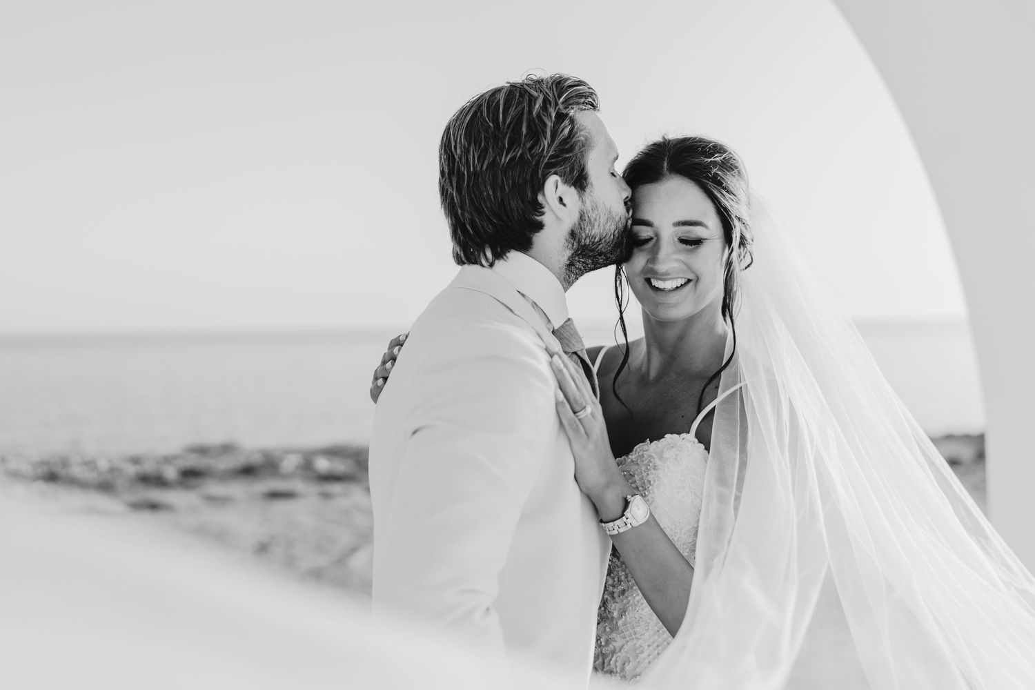 Intimate black and white wedding photograph captured against an ocean backdrop.
