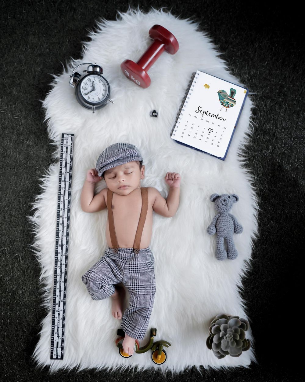 Best baby photography of a sleepiing boy on a white fur blanket with few accessories around