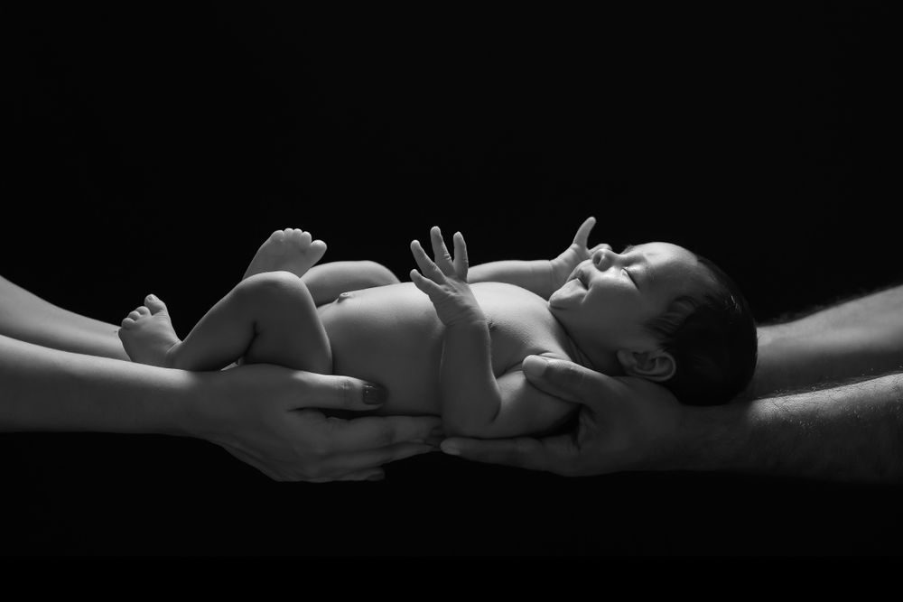 10 day old baby sleeping in the hands of their parents.