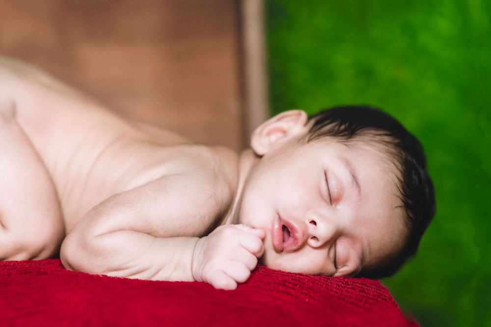 3 months old sleeping baby boy in a red fur blanket in hyderabad