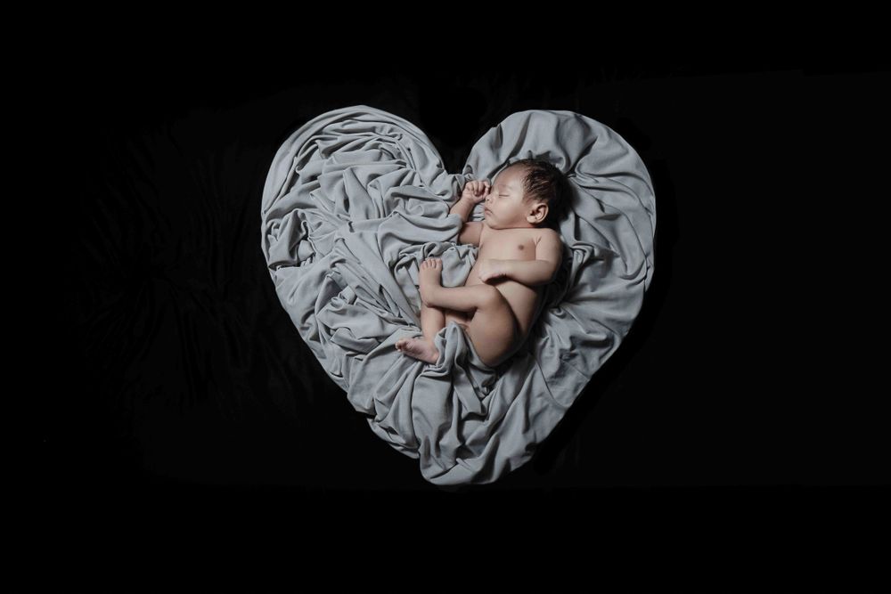Just born baby sleeping on a blanket spread in love shape, Thought by creative baby photographer of little vows