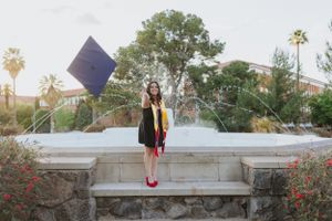 Stone bench graduation photo setting with desert landscaping and palm trees.