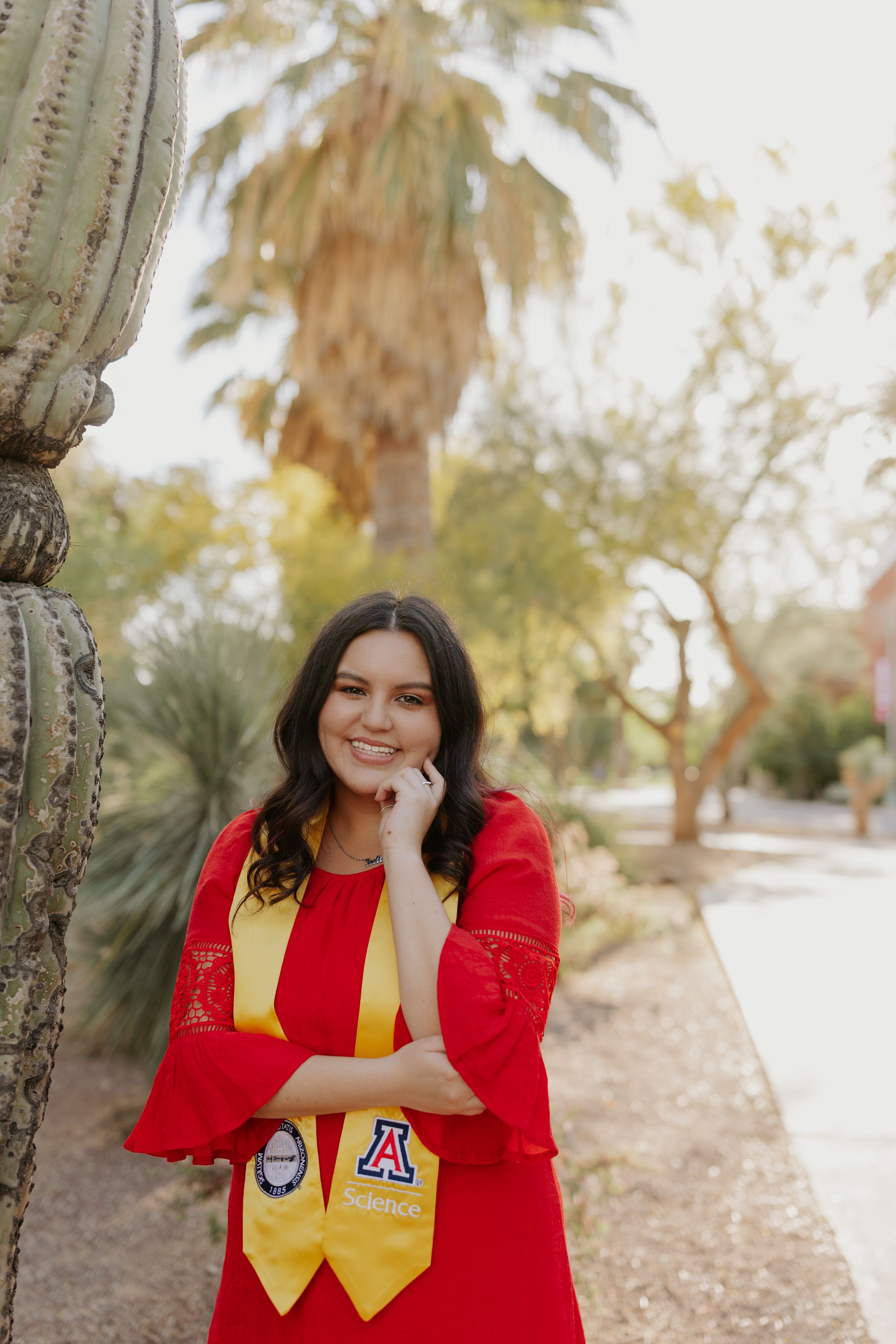 Desert landscape with palm trees and cactus creates natural graduation photo setting.