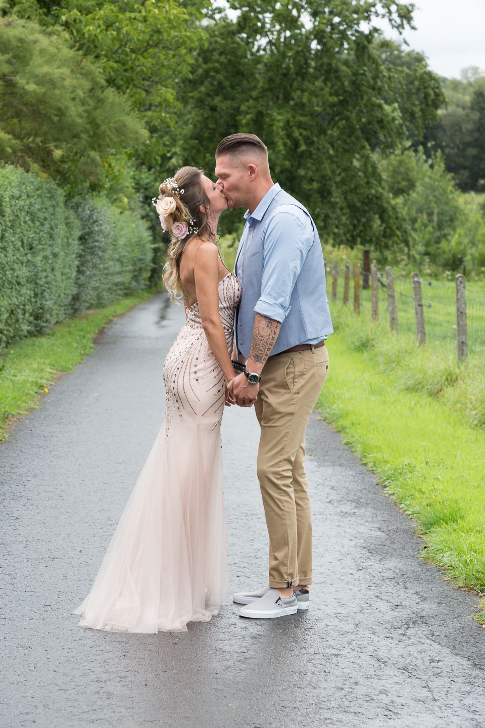 Romantic moment captured on a tree-lined path with formal attire.