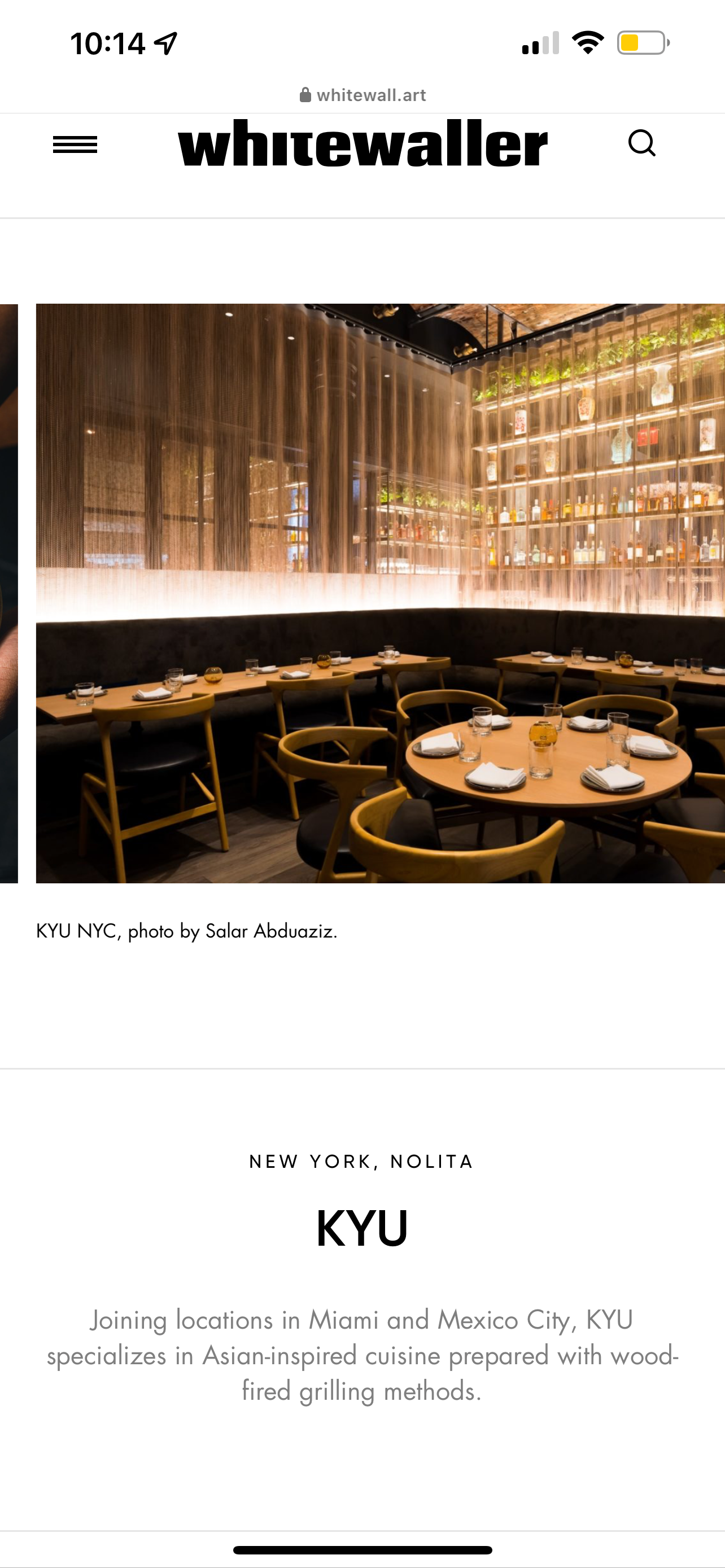 Modern upscale restaurant interior with curved banquettes and backlit bar shelving at KYU NYC.