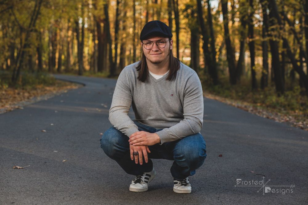 High school senior boy on a road in the woods.