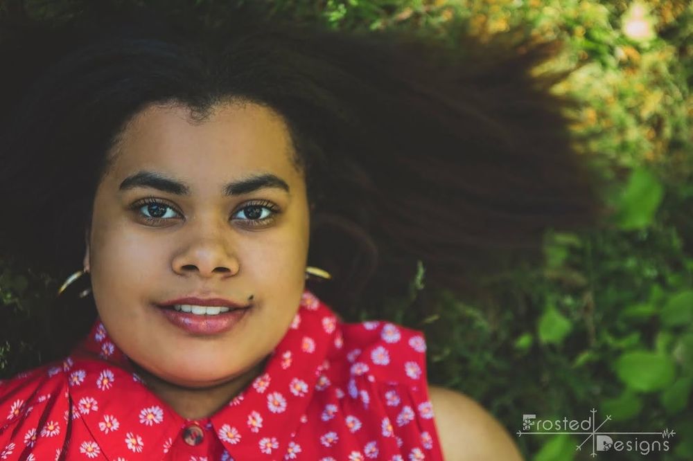 High school senior girl laying down in grass with hair splayed out for senior photography session.