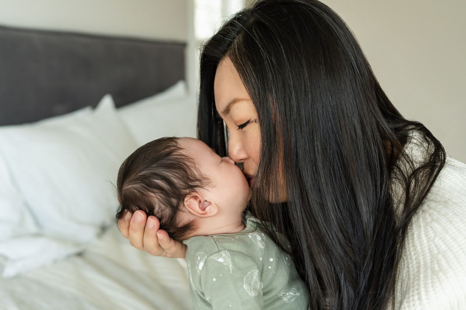 Mother kissing newborn daughter at their home in Seattle.