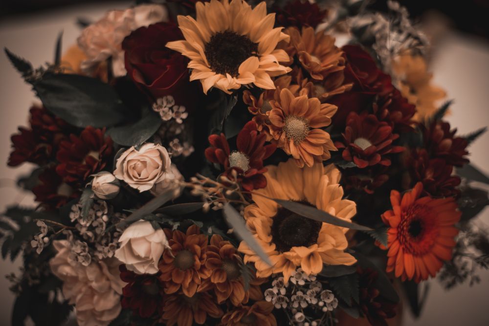 Moody fall floral arrangement with sunflowers, roses and dark burgundy blooms.