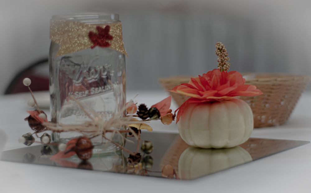 Vintage mason jar and white decorative pumpkin with coral flower on display with rustic fall decor.