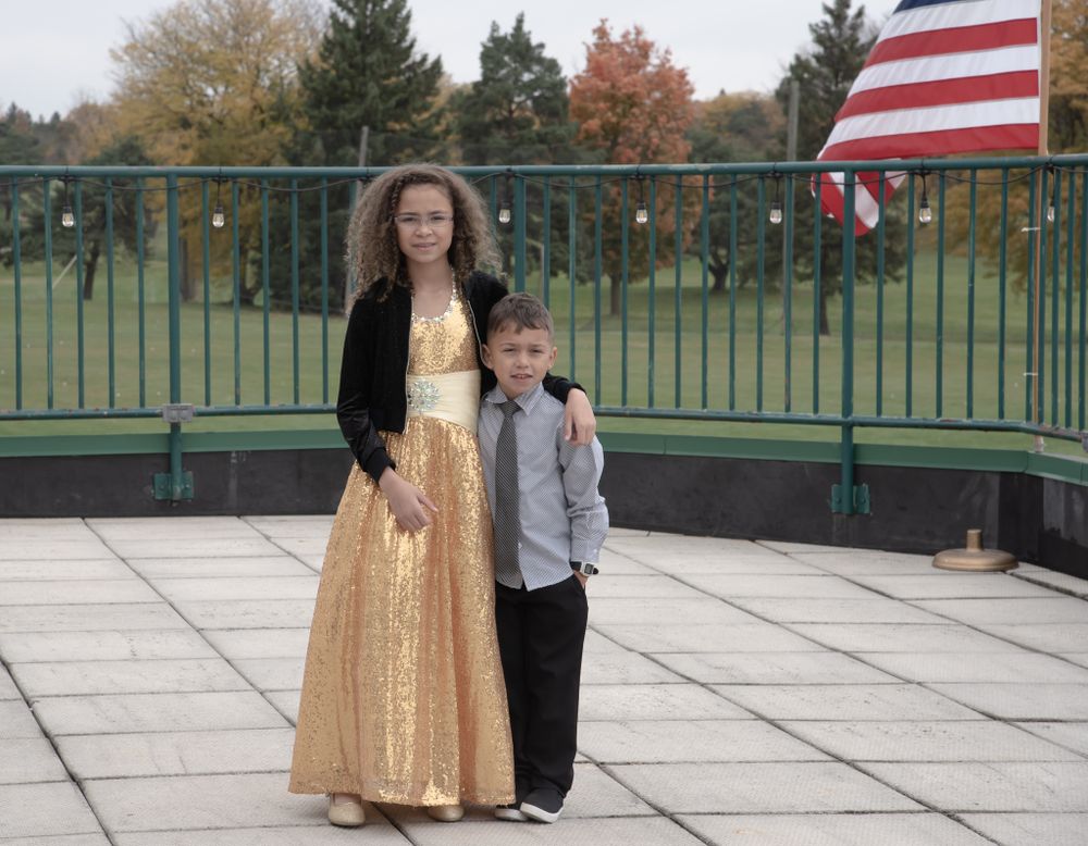 Formal event photo with American flag on outdoor balcony.