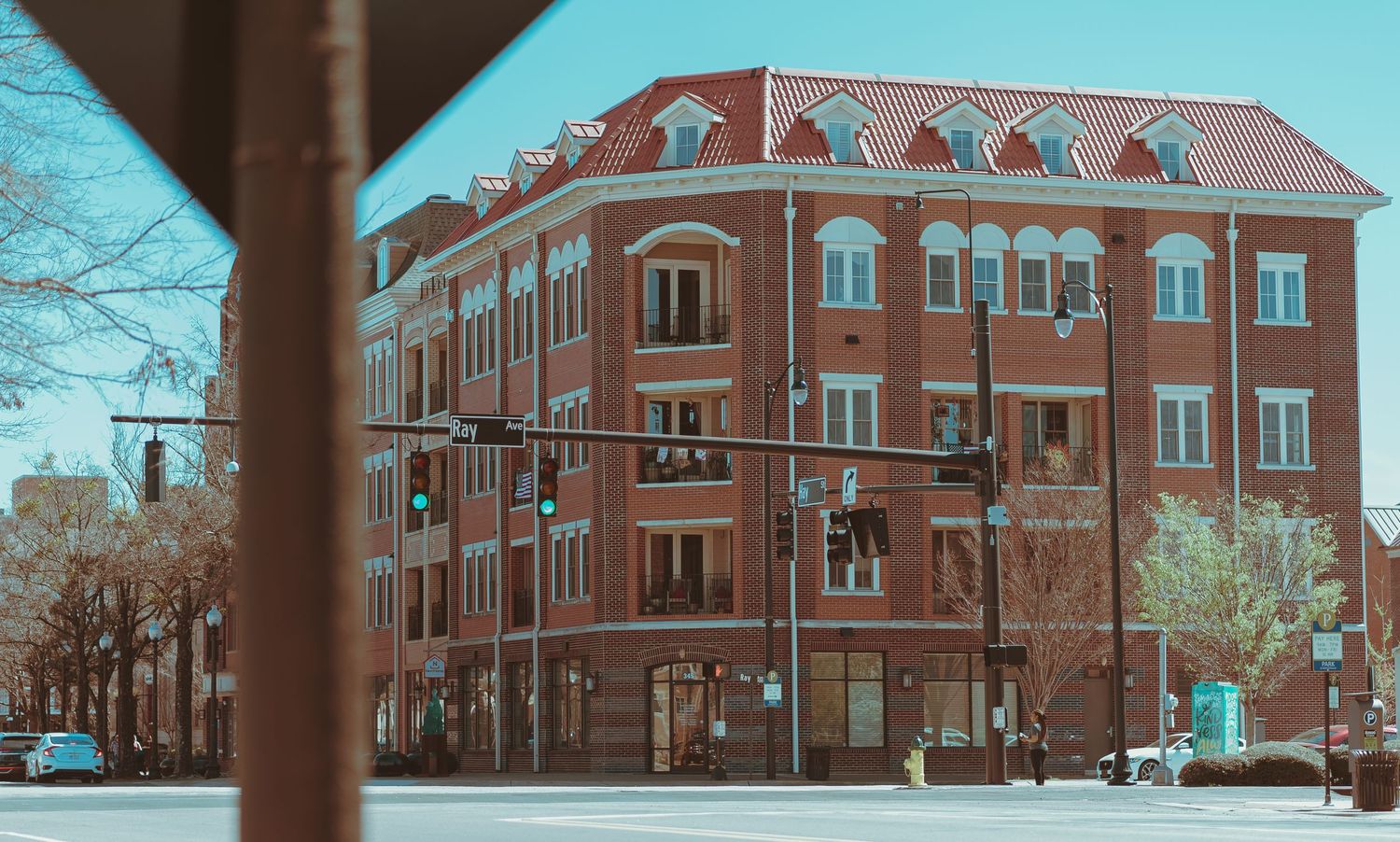 Brick apartment building with arched windows and dormers in vintage teal color grading.