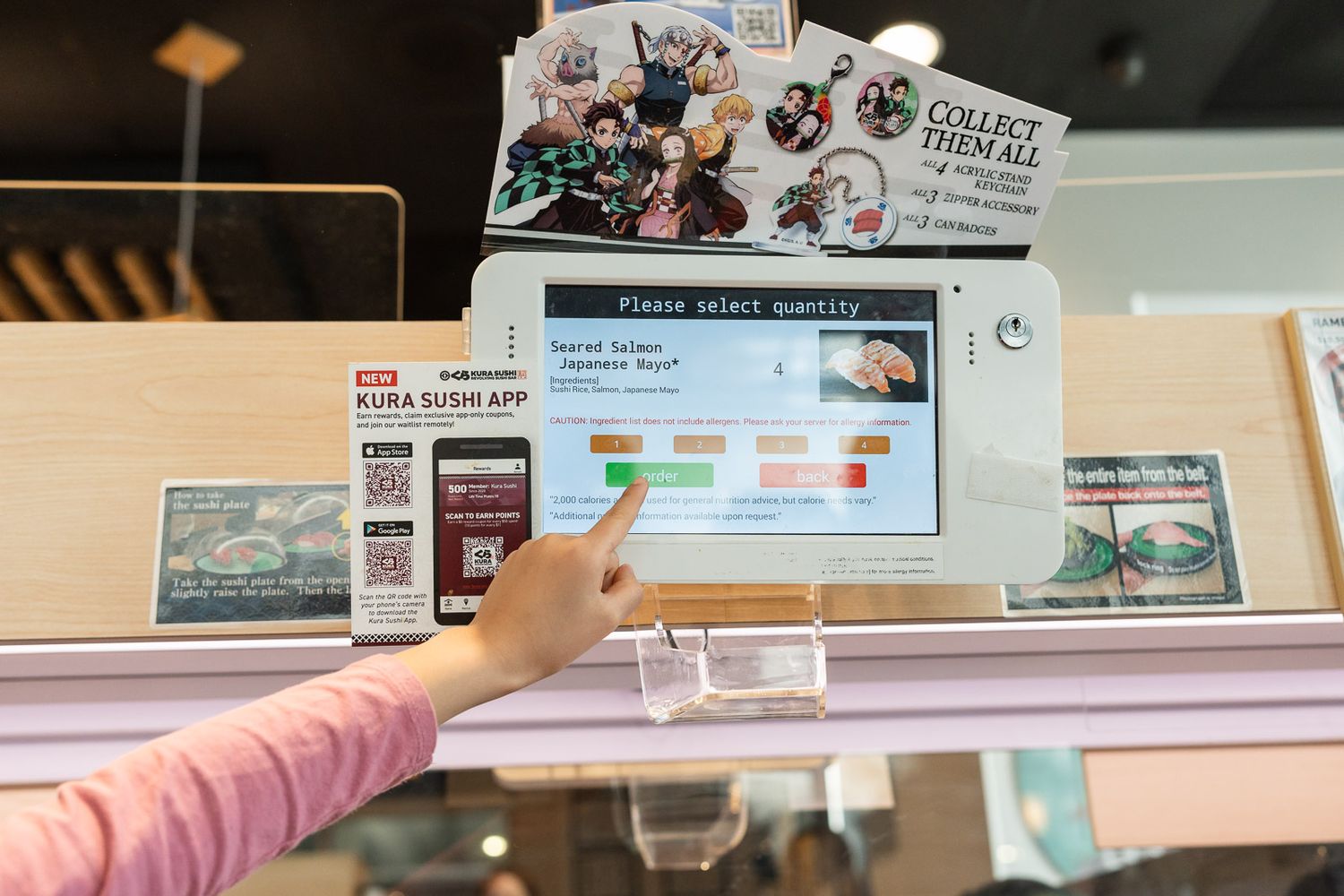 Child using touch screen to select sushi rolls at Kura Revolving Sushi Bar in Bellevue.