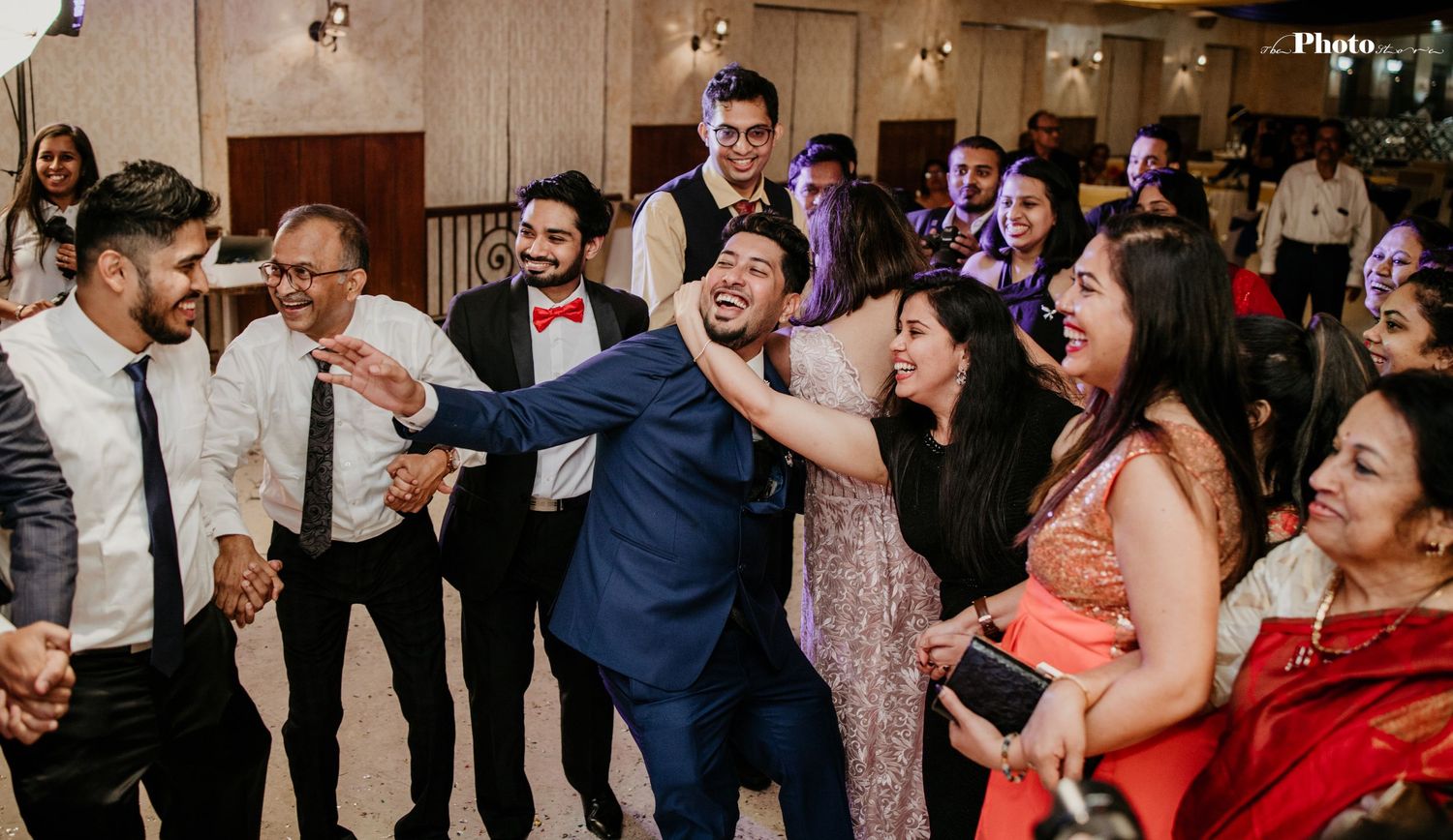 Lively wedding reception with guests dancing and celebrating in formal attire.