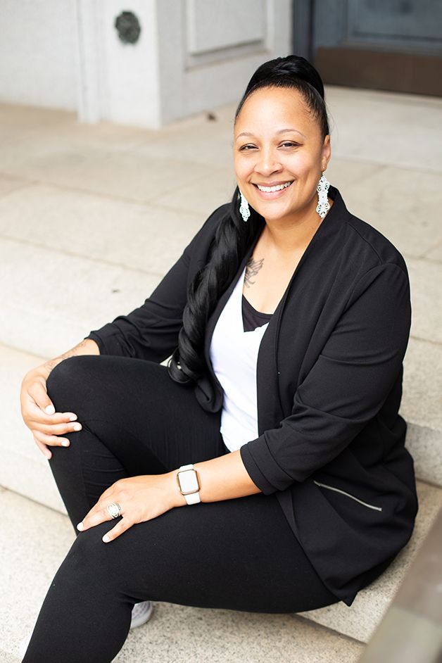 Woman in business attire sitting on white stone steps in downtown Augusta.