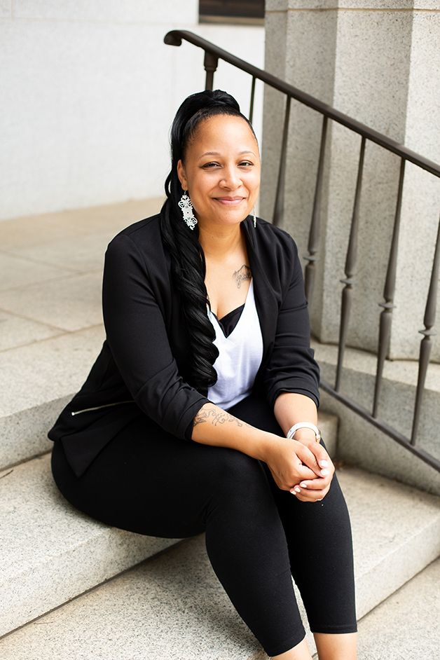 Woman in business attire sitting on white stone steps in historic downtown Augusta, GA.