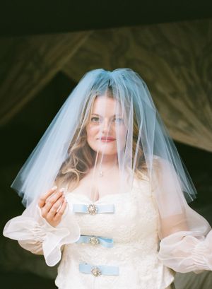 fun, quirky bride with baby blue wedding dress accents posing with her baby blue veil