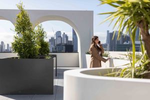 Rooftop terrace with white arches and planters overlooking city skyline.