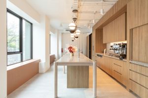 Modern kitchen with wood finishes, pendant lights, and communal table.